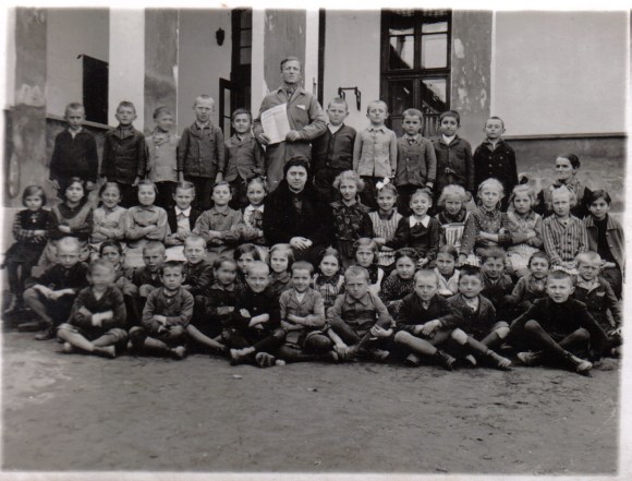 Riha Ilona 2. osztályos diákjai körében 1941-ben, a templom melletti általános iskolában. Tőle balra a harmadik kislány Mag Valéria.
